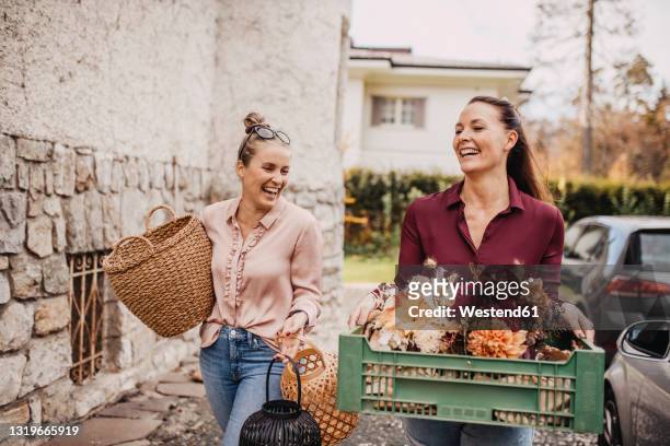 woman with friend carrying flower crate - event planner stock pictures, royalty-free photos & images