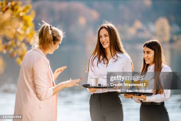 female event planner instructing waitress holding drink trays - platter side bildbanksfoton och bilder