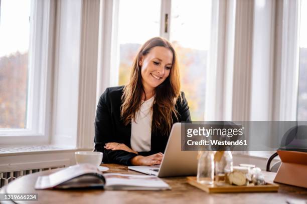 businesswoman using laptop while sitting in office - person in front of computer stock pictures, royalty-free photos & images
