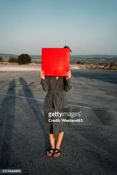 woman covering face with red placard while standing at road - touching face stock pictures, royalty-free photos & images