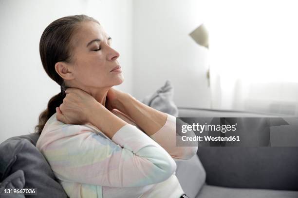 tired woman siting with eyes closed on sofa - exhaustion stock-fotos und bilder