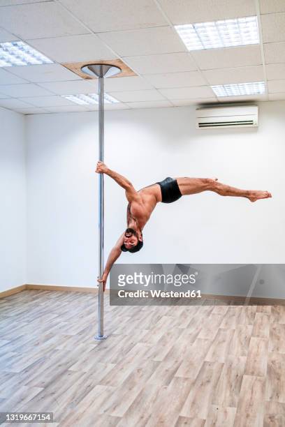 muscular build male acrobat balancing on rod - pole dance stock pictures, royalty-free photos & images