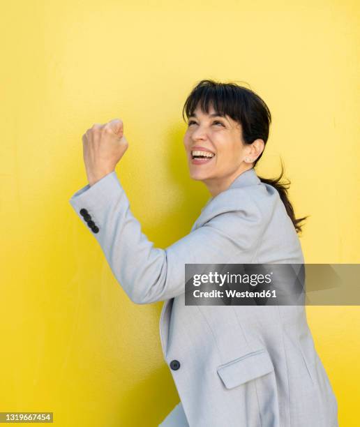 excited businesswoman cheering while standing by wall - business woman cheering stockfoto's en -beelden