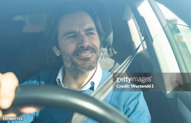 mature male entrepreneur smiling while driving car - business person driving stock-fotos und bilder