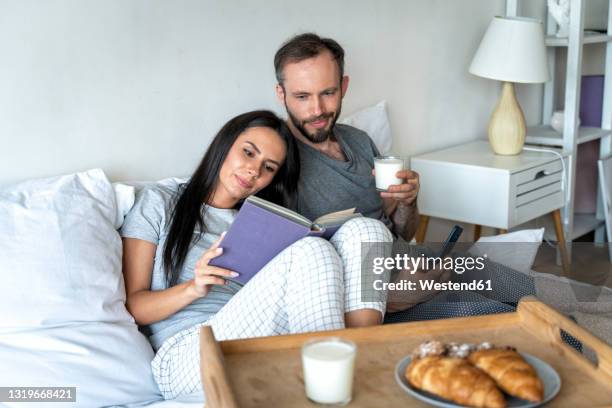 man and woman having breakfast on bed at home - pigiama foto e immagini stock