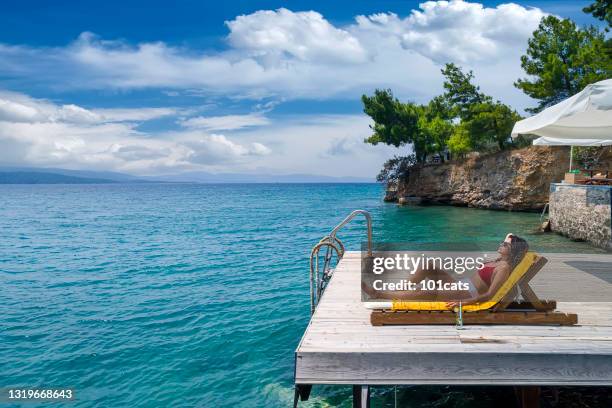 beautiful woman sunbathing alone on a wooden pier in sea aerial photo - marmaris stock pictures, royalty-free photos & images