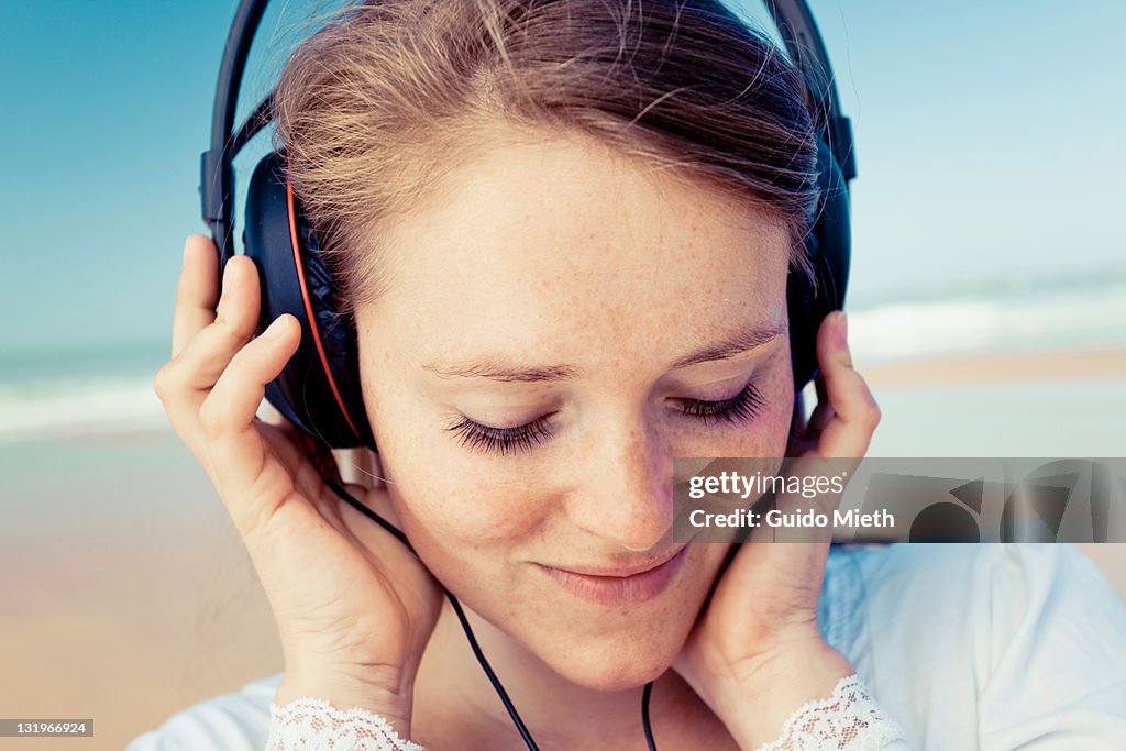 Portrait of women listen to music on beach.