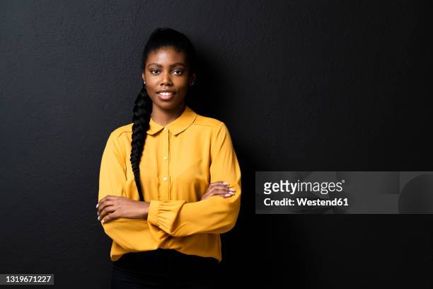 businesswoman with arms crossed standing in front of black wall - black blouse stock pictures, royalty-free photos & images