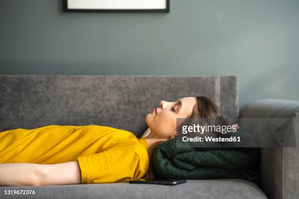 woman relaxing on sofa at home - sleep female handphone stock-fotos und bilder