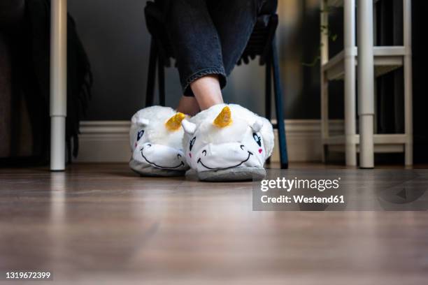 woman wearing fluffy slippers with legs crossed at ankle at home - legs crossed at ankle stock-fotos und bilder