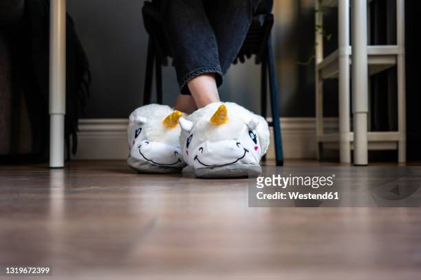 woman wearing fluffy slippers with legs crossed at ankle at home - pantoffel stockfoto's en -beelden