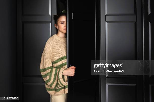 woman staring while opening door of closet - wardrobe stock-fotos und bilder