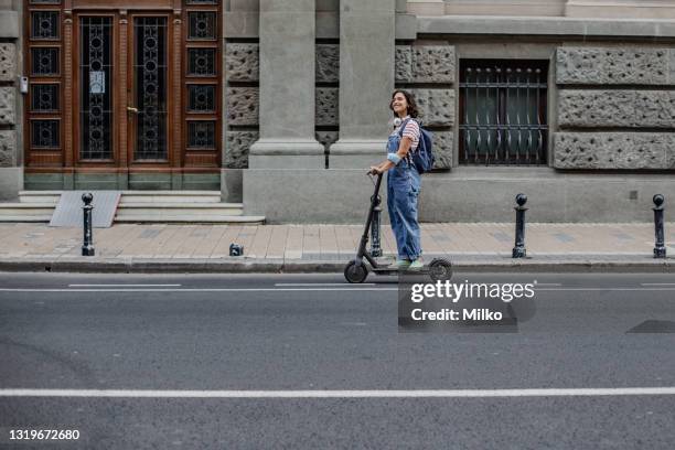 de jonge vrouw berijdt van een elektrische scooter door de stad - step well stockfoto's en -beelden