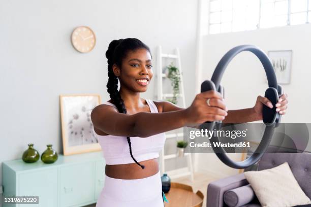 smiling woman exercising with pilates ring at home - cerchio in metallo da pilates foto e immagini stock