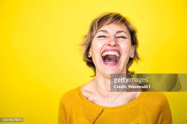 woman laughing in front of yellow background - coloured background lachen stock-fotos und bilder