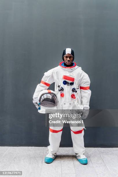 male astronaut standing in front of gray wall - astronaut potrait stock-fotos und bilder