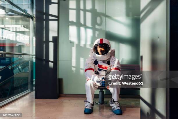 male astronaut waiting on bench in corridor - astronaut sitting stock pictures, royalty-free photos & images