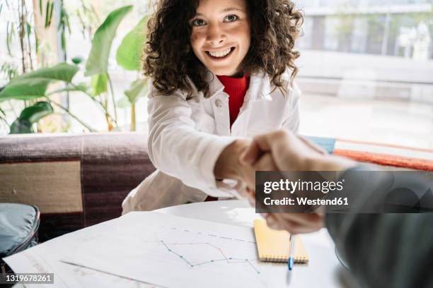 woman shaking hands with man while sitting at table in cafe - pov stock-fotos und bilder