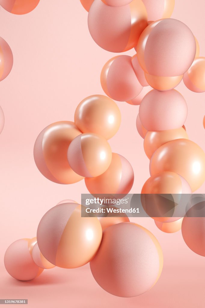 Three dimensional render of pink and orange spheres floating against pink background