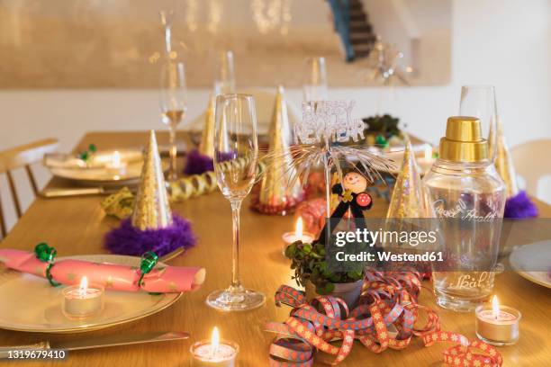 festive laid new years eve table with plates, candles, party hats, champagne flutes and chimney sweep figurines - new years eve dinner stock pictures, royalty-free photos & images