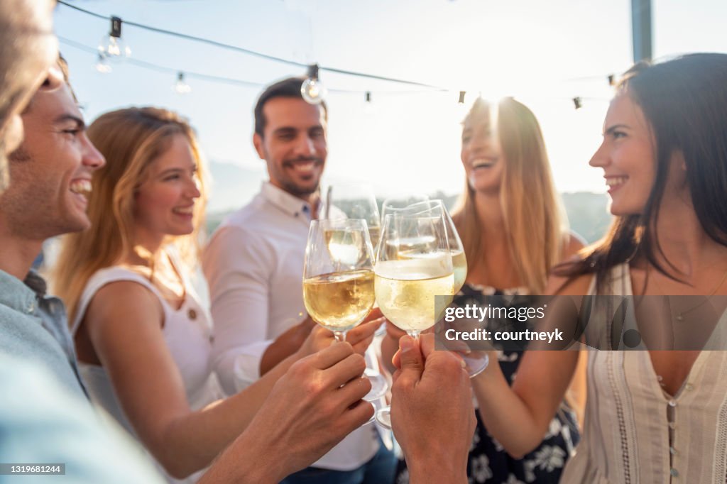 Gruppe von Freunden, die bei Sonnenuntergang Getränke trinken.