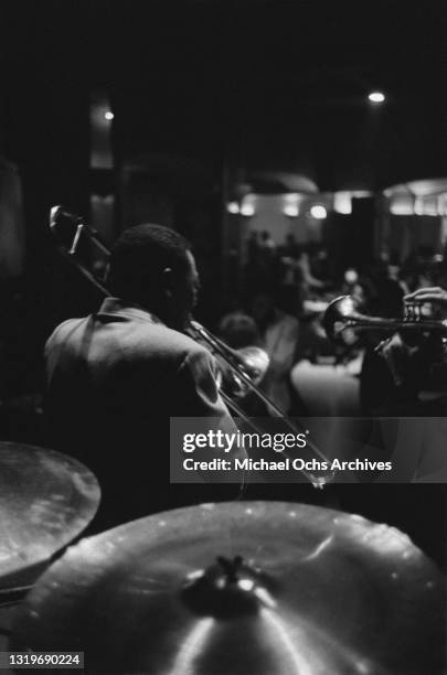 View from the back of the stage showing an unspecified trombonist and an unspecified trumpeter performing at Birdland, a jazz club in the borough of...