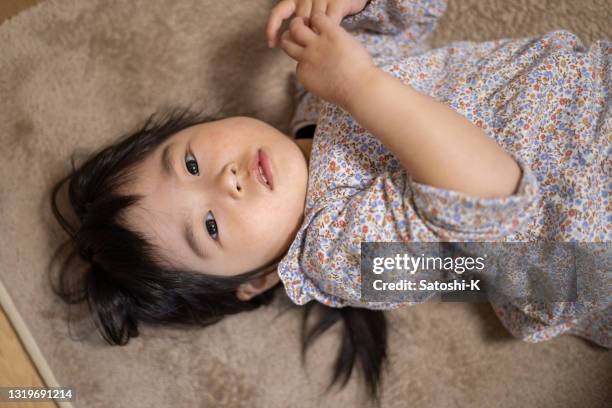 little girl lying on back in living room - camel colored stock pictures, royalty-free photos & images