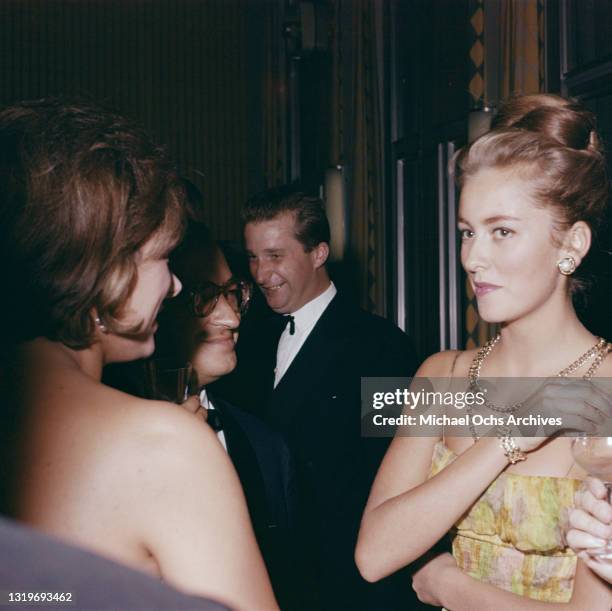 Belgian Royal Paola, Princess of Liege, wearing a yellow, green and pink outfit with spaghetti straps, with a gold necklace and matching bracelet,...