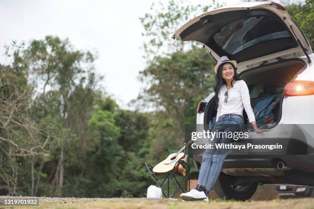 woman traveler sitting on hatchback car with mountain background - asian woman smiling sunrise stock pictures, royalty-free photos & images