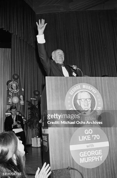 American actor Walter Brennan , his hand raised, speaks from a lectern, on which is written 'George Murphy - For All California' and 'Go Like '70...