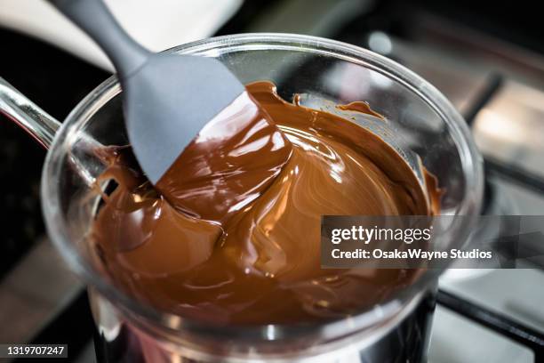 mixing chocolate while melting in transparent glass dish. - molten stock pictures, royalty-free photos & images