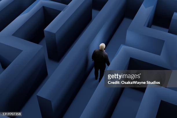 high angle view of male figure walking through maze. - maze stock pictures, royalty-free photos & images