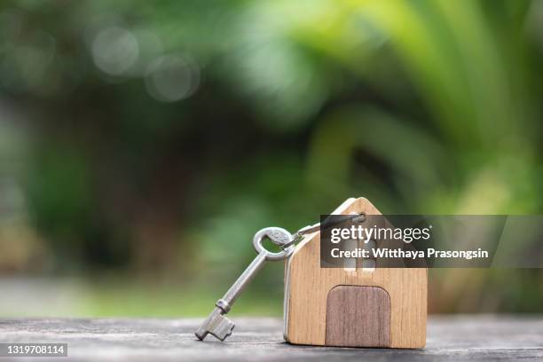 house keys on a house shaped keychain on wooden background. concept for real estate, moving home or renting property on dark wood - home key stockfoto's en -beelden