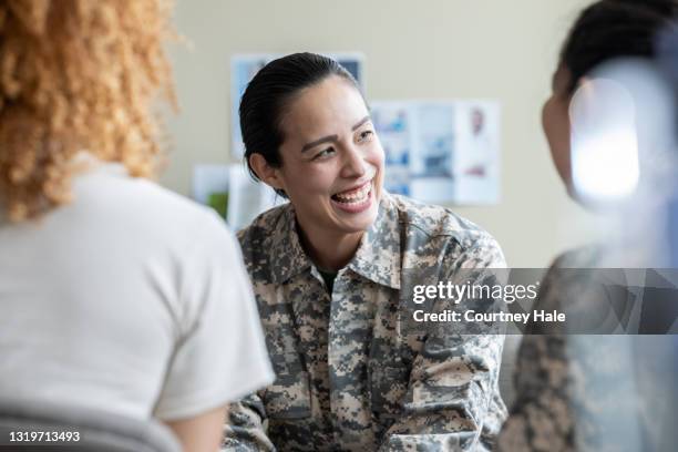 erwachsene militärfrau lächelnd während gruppentherapie diskussion - gruppe zuhören hilfe stock-fotos und bilder