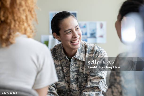mujer militar adulta sonriendo durante discusión de terapia de grupo - war veteran fotografías e imágenes de stock
