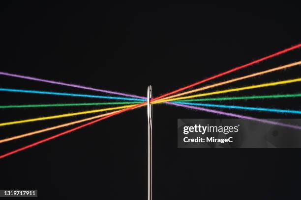 rainbow colored threads through needle eyelet - string fotografías e imágenes de stock