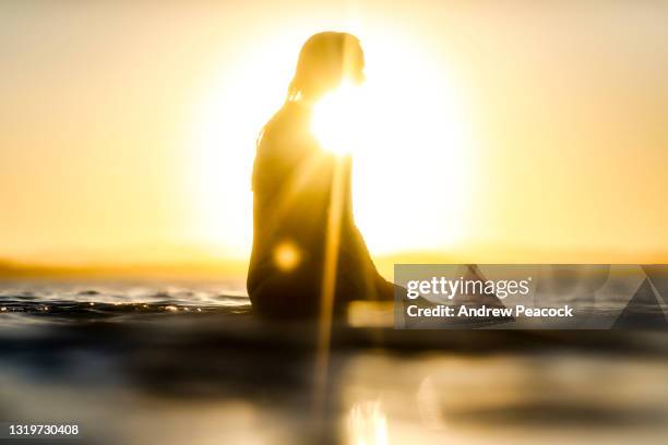 a woman on a surfboard at sunset. - noosa heads stock pictures, royalty-free photos & images