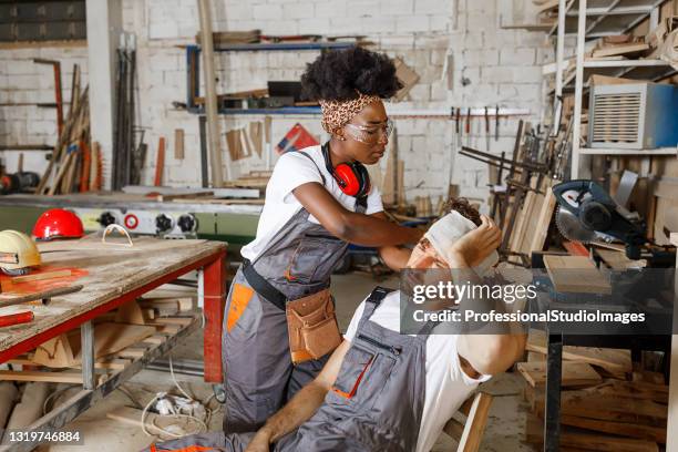 a carpenter is receiving help from his female colleague after a head injury. - concussion stock pictures, royalty-free photos & images