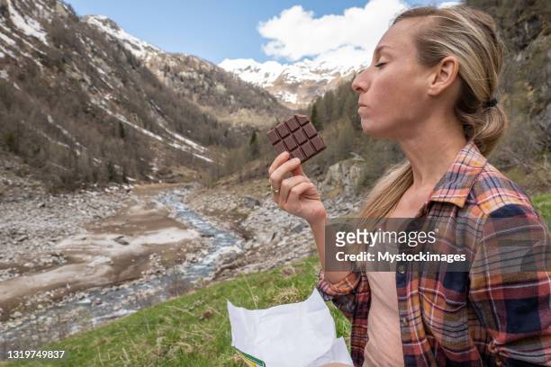 woman eating swiss chocolate in nature - eating dark chocolate stock pictures, royalty-free photos & images