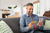 Mixed race man paying online on mobile phone