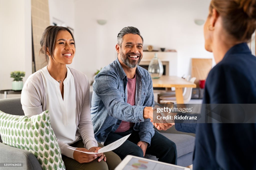 Multiethnisches Paar Handshake mit Berater zu Hause