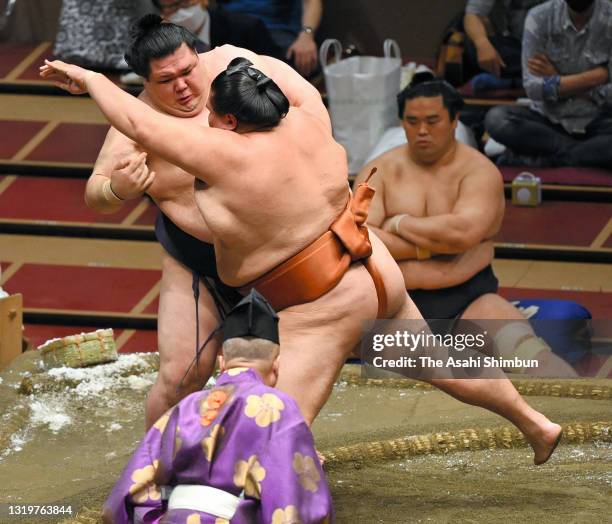 Komusubi Mitakeumi pushes Onosho out of the ring to win during day thirteen of the Grand Sumo Summer Tournament at Ryogoku Kokugikan on May 21, 2021...