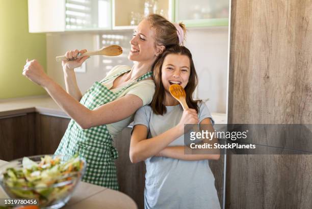 young mother and daughter having fun singing in the kitchen - mother food imagens e fotografias de stock