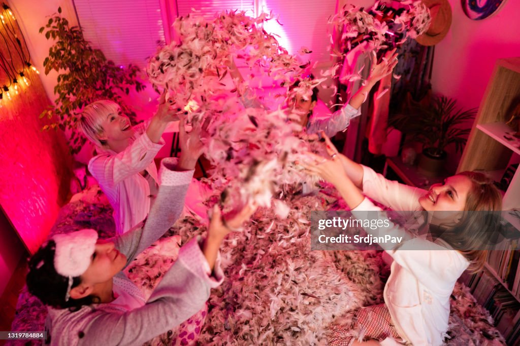 High-angle view of smiling young women having fun with feathers