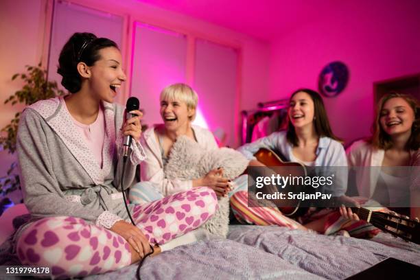 young women laughing while having fun on a karaoke slumber party - karaoke stock pictures, royalty-free photos & images