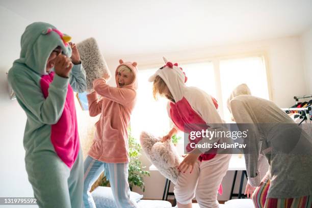 joyful young women having fun during a pillow fight - pillow fight stock pictures, royalty-free photos & images