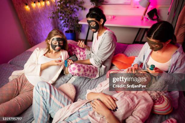 hochwinkelansicht junger freundinnen, die auf einer sleepover-party gemeinsam schönheitsbehandlungen erhalten - übernachtungsparty stock-fotos und bilder