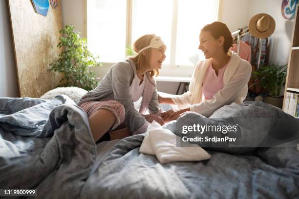 two young women in bed laughing together - pyjamas stock pictures, royalty-free photos & images