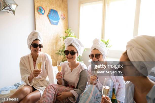 giovani donne sorridenti che parlano e bevono champagne ad una festa di sonno - addio al nubilato foto e immagini stock