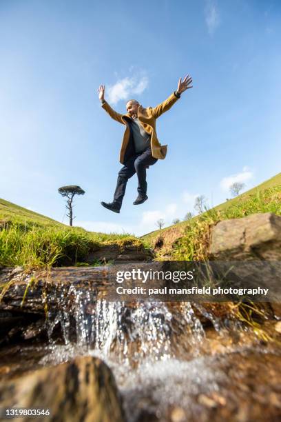 man jumping over stream - leap of faith modo di dire inglese foto e immagini stock